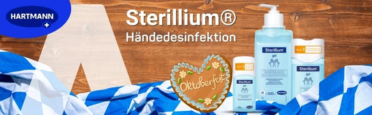 Werbebild von Hartmann für Sterillium® Händedesinfektion mit Oktoberfest-Motiv. Auf einem Holzhintergrund stehen verschiedene Sterillium-Produkte, darunter Flaschen mit Gel und Lösung in unterschiedlichen Größen. Davor liegt ein blau-weiß kariertes Stofftuch im bayerischen Stil sowie ein Lebkuchenherz mit der Aufschrift „Oktoberfest“. Links oben befindet sich das Hartmann-Logo.