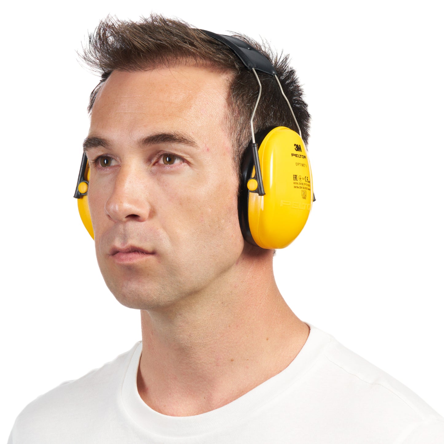 A man with short brown hair wears a bright yellow 3M™ PELTOR™ Optime™ I Ear Muffs H510A (SNR 27 dB) from 3M Deutschland GmbH and a simple white shirt. He looks straight ahead against a plain white background.