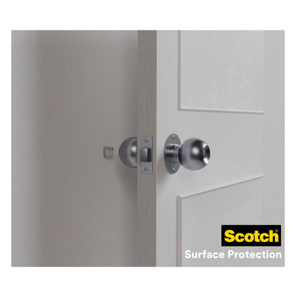 A white door with a round silver knob stands open and dents the light wall. 3M Deutschland GmbH Scotch® Shock Absorbing Elastic Bumpers for Walls SP91A64 (self-adhesive, transparent, Ø 22 mm) provide effective wall protection; logo visible at the bottom right.