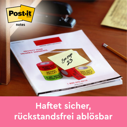 Ein Post-it® Zettel (gelb, 76x102 mm, 100 Blatt) der 3M Deutschland GmbH mit der Aufschrift "Siehe Seite 23" ist an einem Dokument auf einem Schreibtisch befestigt; das Post-it-Logo befindet sich oben links und ein pinkfarbener deutscher Text erscheint unten auf dem Zettel.