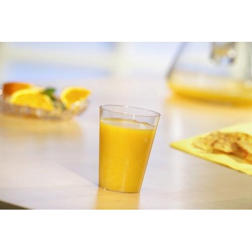 A Starpak 40 drinking cup, PS 0.1 l Ø 5.5 cm · 7.5 cm crystal-clear disposable cup is filled with orange juice on a light table. In the background are orange slices and a jug – ideal for parties and events.