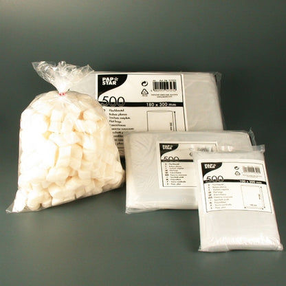 Several Starpak 500 flat bags made of transparent LDPE from the Starpak brand lie on a gray surface; one bag contains loose white cubes, others show labeled packaging solutions.