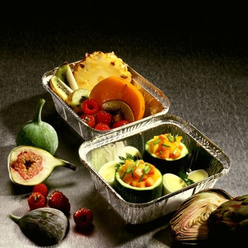 Two Starpak 10 trays, aluminum with PP-coated insert lids, feature fresh pineapple, kiwi, raspberries, figs, pumpkin, and zucchini on a dark surface, with whole figs and an artichoke beside them—ideal for food storage.