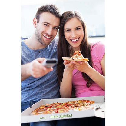 A smiling man and a smiling woman sit on a sofa. The woman holds a piece of pizza from an open PAPSTAR 100 pizza box, cellulose "pure" square from PAPSTAR GmbH, while the man points at it with a remote control. Both look into the camera.