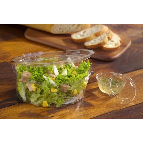 A clear, round Starpak 100 lid (PS, Ø 6.7 cm, 1 cm high) seals a plastic container with green salad, corn, and meat, in the background, sliced baguette is on a wooden board.