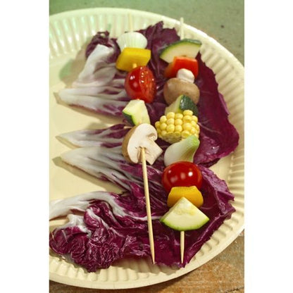 A cardboard tray from PAPSTAR GmbH holds three raw vegetable skewers - mushrooms, cherry tomatoes, onion, zucchini, bell pepper, and corn - on purple cabbage leaves, with PAPSTAR wooden skewer sticks "pure", Ø 3.5 mm, 20 cm long.