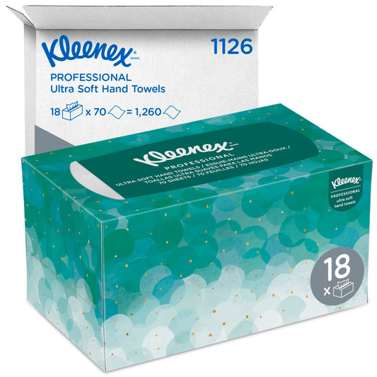 Eine Schachtel Kleenex® Ultra™ Handtücher - Interfold von Kimberly-Clark GmbH in hygienischem, gepunktetem Design steht vor der geöffneten Versandverpackung. Die Schachtel enthält 18 Packungen mit je 70 weißen, mittelgroßen Handtüchern.