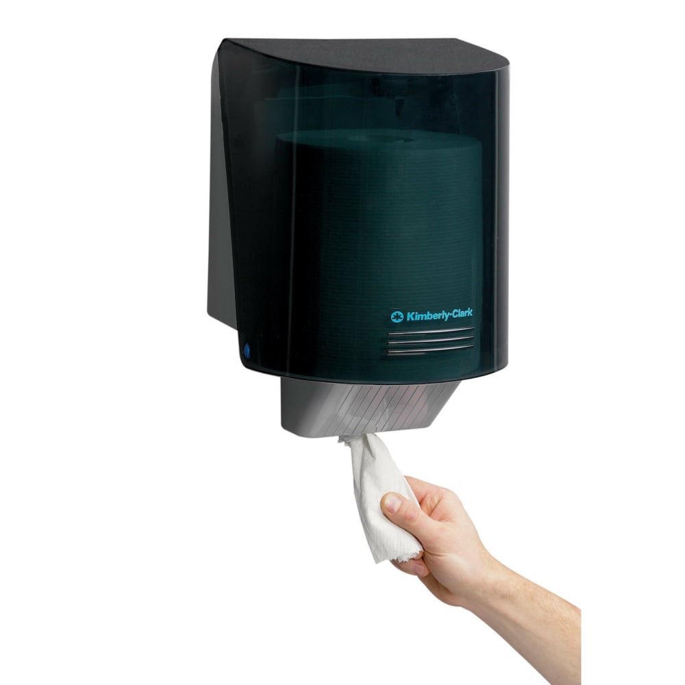 A hand pulls a paper towel from the wall-mounted Kimberly-Clark Professional™ wiper dispenser - central pull in gray, ensuring hygienic towel removal. Brand: Kimberly-Clark GmbH. 1 dispenser | carton (1 dispenser).