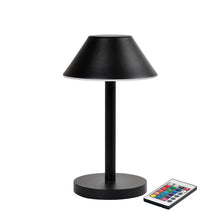 Die LED-Lampe Zelda Midi von Duni GmbH in modernem Graphit-Design mit rundem Sockel und konischem Schirm steht neben einer Fernbedienung mit bunten Tasten - die ideale, energieeffiziente Beleuchtungslösung.