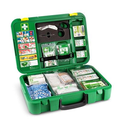 An opened green Orkla Wound Care AB First Aid Kit DIN | Package (1 piece) contains bandages, gauze, antiseptic wipes, scissors, an instant cold pack, adhesive tape, gloves, and a first aid guide in the lid.