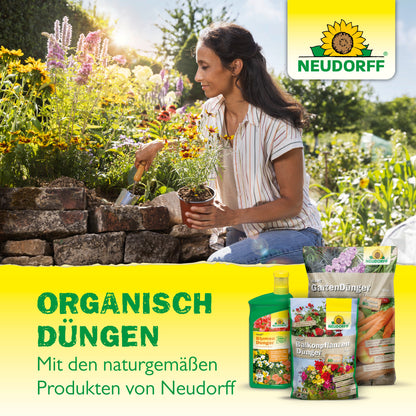 Eine Frau pflanzt Blumen an einem Hochbeet mit einer Kelle; davor steht Azet RosenDünger von Neudorff Shop. Der deutsche Text wirbt für die organische Düngung von blühenden Rosen mit dem natürlichen Azet RosenDünger von Neudorff Shop.