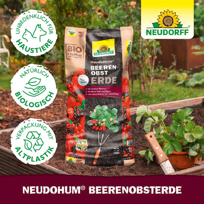 A bag of NeudoHum Berry Fruit Soil from the Neudorff Shop lies on a raised bed with strawberries and a trowel; eco-friendly and pet-friendly symbols show that it is ideal for fruit in pots or on the balcony.