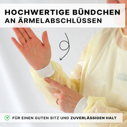 Eine Person trägt den ARNOMED Virendichter Einweg Schutzkittel von ARNOWA GmbH in Gelb und zeigt auf die weiße Manschette am Ärmel. Der Text auf Deutsch hebt hochwertige Bündchen für sicheren Sitz und festen Halt hervor.