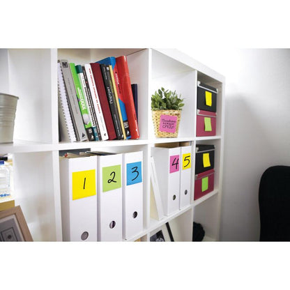 A white bookshelf houses folders with colorful numbers 1-5, books, small boxes, and a potted plant. Post-it® notes in various neon colors (3M Deutschland GmbH) are attached to boxes and folders, facilitating organization.