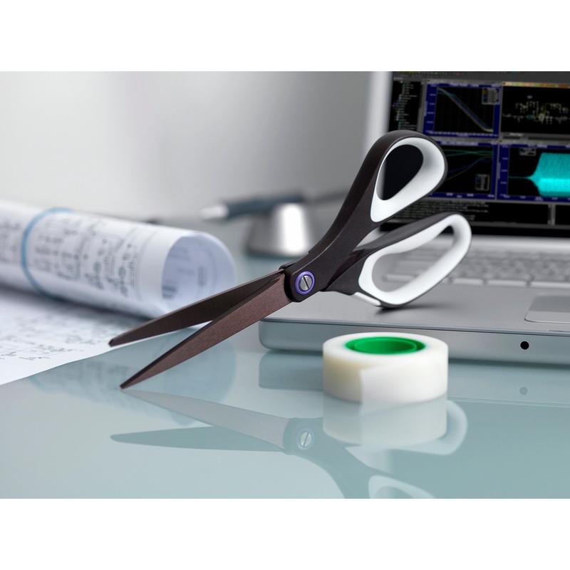A 3M Deutschland GmbH Scotch™ titanium scissors, 20 cm, a roll of clear tape, documents, and a laptop with charts on the screen are placed on a glass table.