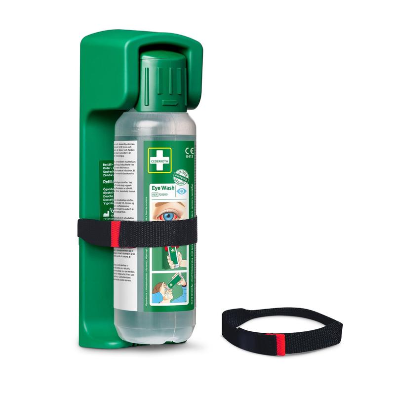 A green, wall-mounted eye wash station contains a Cederroth eye wash bottle 500 ml with illustrated instructions and an Orkla Wound Care AB strap for wall mounting; an additional strap (1 piece) is attached in front.