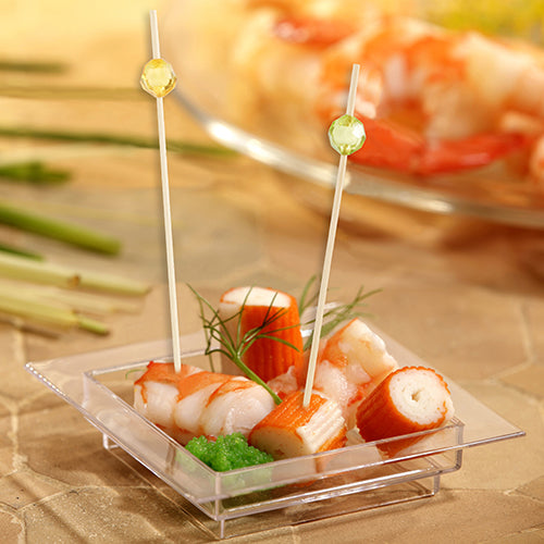 In a square, transparent plastic dish are imitation crab, green roe, and dill, served with two PAPSTAR 100 Fingerfood - Picks from PAPSTAR GmbH with round tips for easy picking.