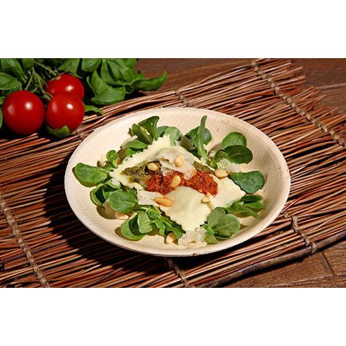 Ravioli with tomato sauce, pesto, pine nuts, and cheese, served on PAPSTAR 25 bowls, palm leaf "pure" from PAPSTAR GmbH - ideal for sustainable events. Fresh cherry tomatoes and greens complete the eco-friendly presentation.