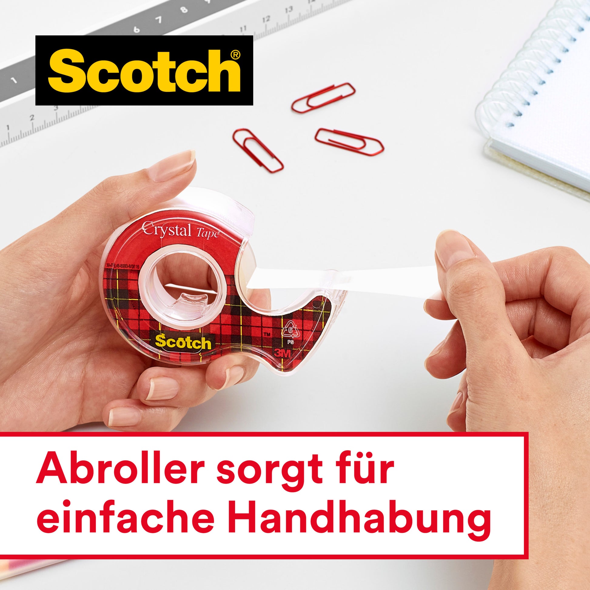 Eine Person zieht einen Streifen Scotch® Crystal Klebeband (19 mm x 15 m, 1 Rolle + Handabroller) von 3M Deutschland GmbH. Zwei Hände erscheinen mit Büromaterial auf einem weißen Schreibtisch. Am unteren Rand ist ein deutscher Text zu sehen.