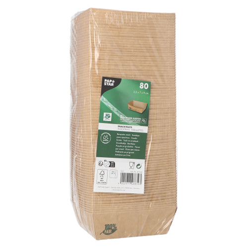 A packaged pack of 80 PAPSTAR snack trays "pure" brown "100% Fair" from PAPSTAR GmbH stands upright, with a label on the front displaying product details and symbols for environmental friendliness and biodegradability; the clear packaging reveals stacked trays inside.