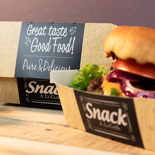 A cardboard tray with the inscription "Snack A La Carte" contains a hamburger with lettuce, tomato, and onion. In the background is a PAPSTAR 50 burger boxes, cardboard "pure" "Good Food" by PAPSTAR GmbH: Great Taste Good Food! Pure & Delicious.