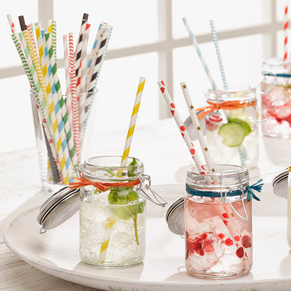 Mason jars with drinks and ice, each with a PAPSTAR 100 straws paper "pure" (Ø 6 mm · 20 cm, from PAPSTAR GmbH), are on a white tray. More eco-friendly straws are in a glass in front of a window backdrop.