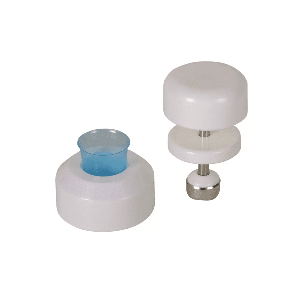 Against a white background, two white plastic kitchen tools can be seen. The tool on the left has a cylindrical shape with a blue plastic insert, while the tool on the right is an AMPri tablet crusher for medicine cups by AMPri Handelsgesellschaft mbH, which consists of two white discs connected by a stainless steel rod with a metal base.