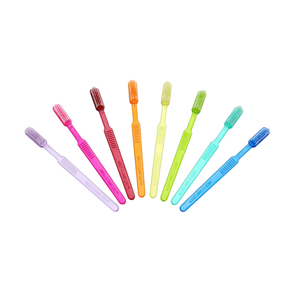 Seven bright AMPri MED-COMFORT Dental PS disposable toothbrushes with toothpaste are neatly arranged in a row. From left to right, the colors are purple, pink, red, orange, yellow, green, and blue. Each has a similar design with soft bristles, perfect for dental care on the go.