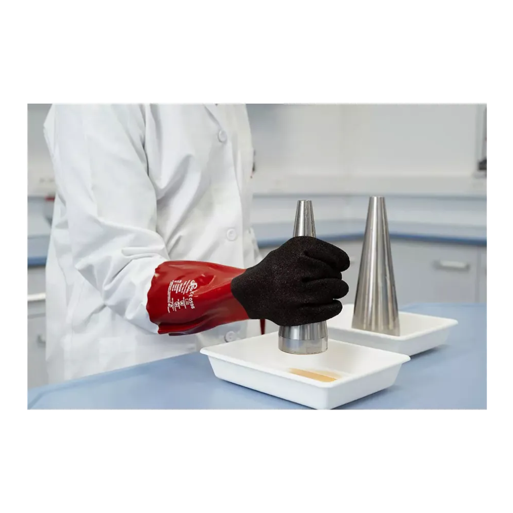 A person in a lab coat and red AMPri SolidSafety Chem MaxGrip chemical protective gloves M - L is carefully holding a metal cone over a white dish. An identical dish with its own metal cone is placed next to it on the blue laboratory tabletop, ensuring protection against acids throughout the experiment.