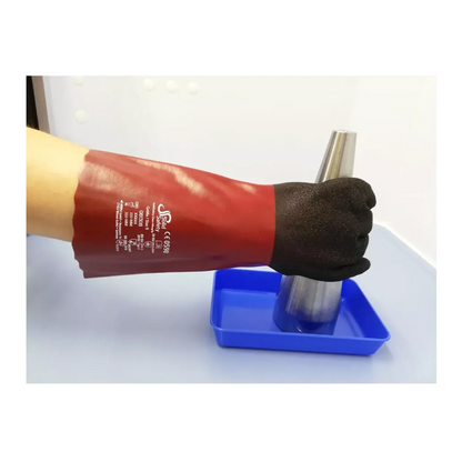 A person is wearing a red AMPri SolidSafety Chem MaxGrip glove with black fingers and white markings and is holding a metallic cone over a blue tray. The glove, known for its protection against acids and abrasion resistance, stands out against the plain, light background.