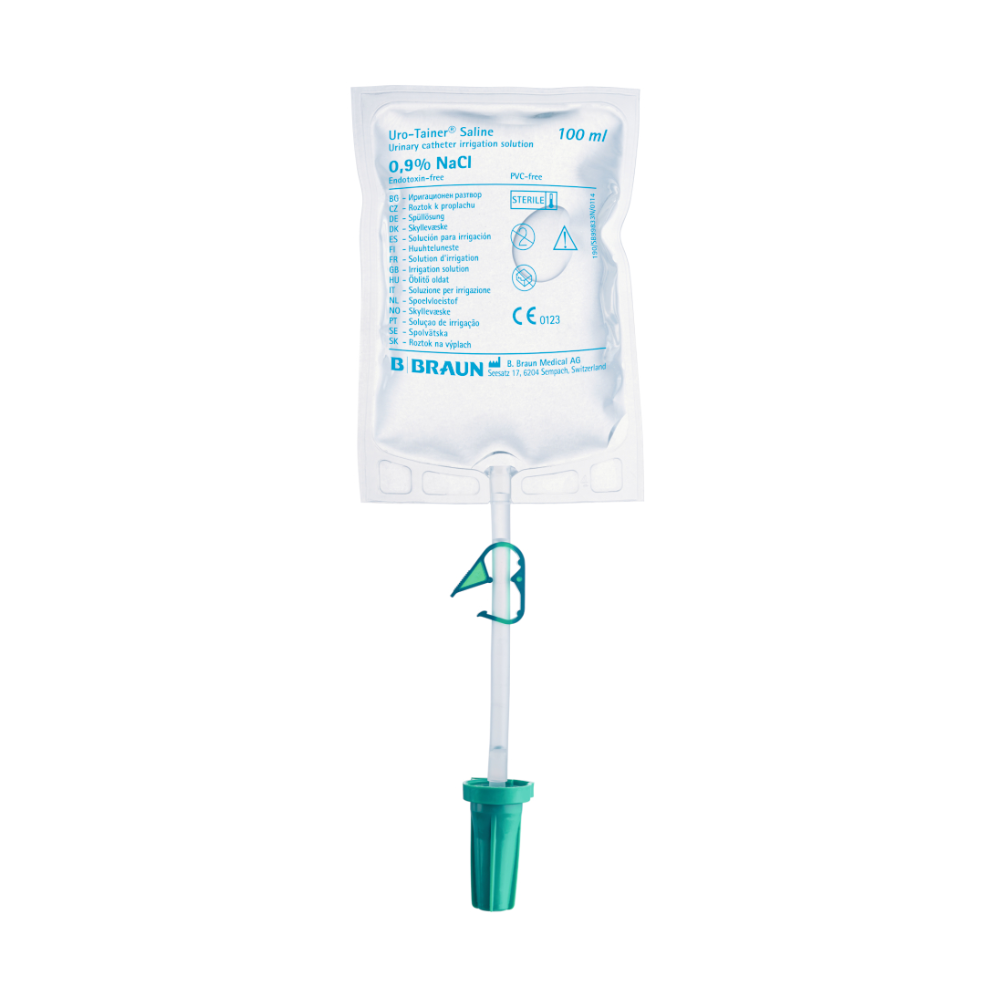 A 100 ml bag of saline solution 0.9% NaCl from the brand B. Braun Deutschland GmbH & Co. KG is hung with a green plastic hook. The B.Braun Uro-Tainer® NaCl is designed for intravesical instillation and carries various medical information and symbols on its front.