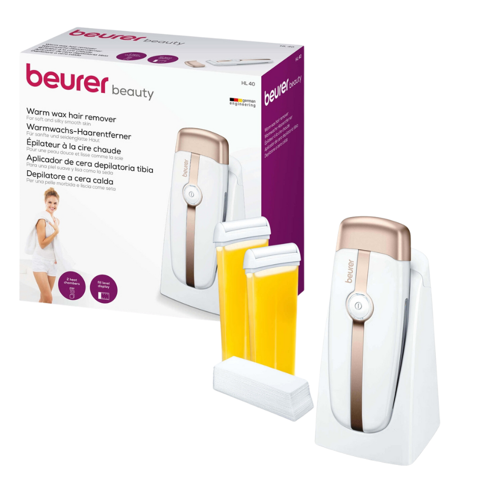 Pictured is a Beurer HL 40 warm wax hair removal set from Beurer GmbH. The set includes the main device, two beeswax cartridges, a cleaning cloth, and in the background, the product's packaging box. The box contains product information and a picture of a woman.