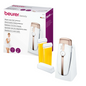 Pictured is a Beurer HL 40 warm wax hair removal set from Beurer GmbH. The set includes the main device, two beeswax cartridges, a cleaning cloth, and in the background, the product's packaging box. The box contains product information and a picture of a woman.