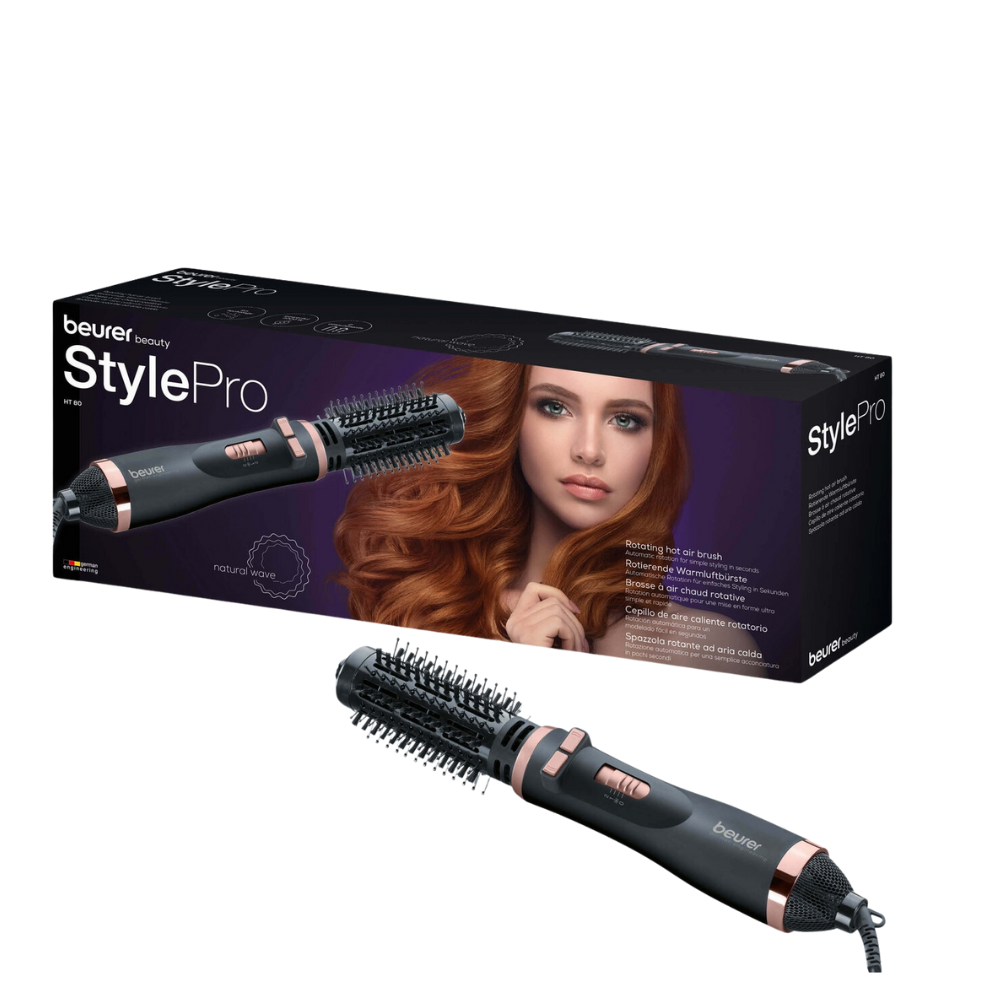 A Beurer HT 80 Rotating Hot Air Brush from Beurer GmbH is pictured in front of its packaging box. The box shows an image of a woman with styled hair and product details. The brush has a cylindrical design with bristles and an attached power cord.