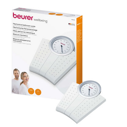 A photo showing a mechanical personal scale Beurer MS 50 | Package (1 piece) by Beurer GmbH with its packaging. The scale has a white, non-slip surface with a distinctive round, analog weight display on top. Next to the scale, the packaging box shows a picture of the scale and a picture of two smiling people.