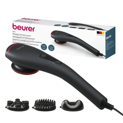 A Beurer massage device MG 24 from Beurer GmbH is depicted with its packaging in the background. The massage device has a black casing with a red accent and several detachable heads arranged at the front: a brush attachment, a multipoint head, and a rounded head. The product packaging includes images and text showing its heating function.