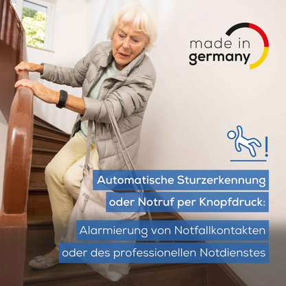 Elderly woman in a light gray coat holds onto a wooden handrail while climbing stairs. The text highlights the automatic fall detection and emergency call function via the Beurer emergency bracelet EC 70 SafePlus, with "made in Germany" branding and safety symbols.