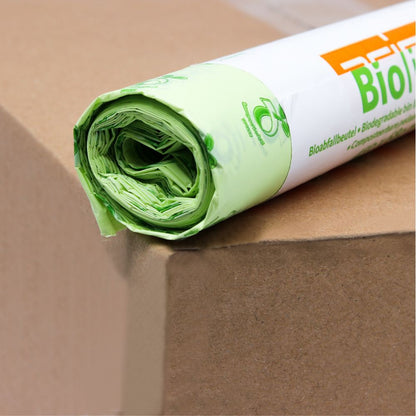 A roll of light green DEISS organic waste bags 30 liters, 06030, which are 100% compostable, lies on a brown box. The packaging is partially visible and shows an eco-friendly logo and the word "Bio" in bold orange letters of EMIL DEISS KG (GmbH + Co.).