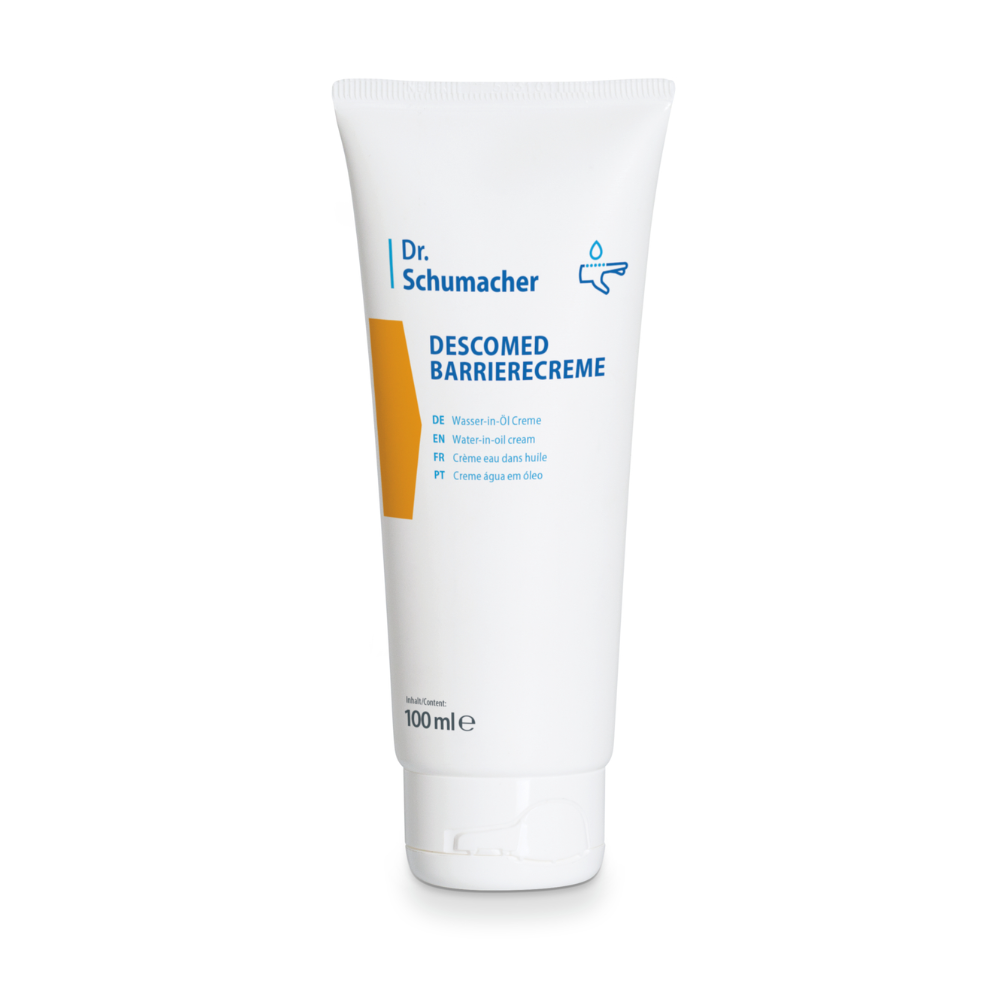 A white tube of Dr. Schumacher Descomed Barrier Cream with a capacity of 100 ml, featuring the product name in blue lettering and a small graphic of a water droplet. On the front of the tube, various translations of 'Barrier Cream' are visible, highlighting its identity as a water-in-oil cream for skin area care.