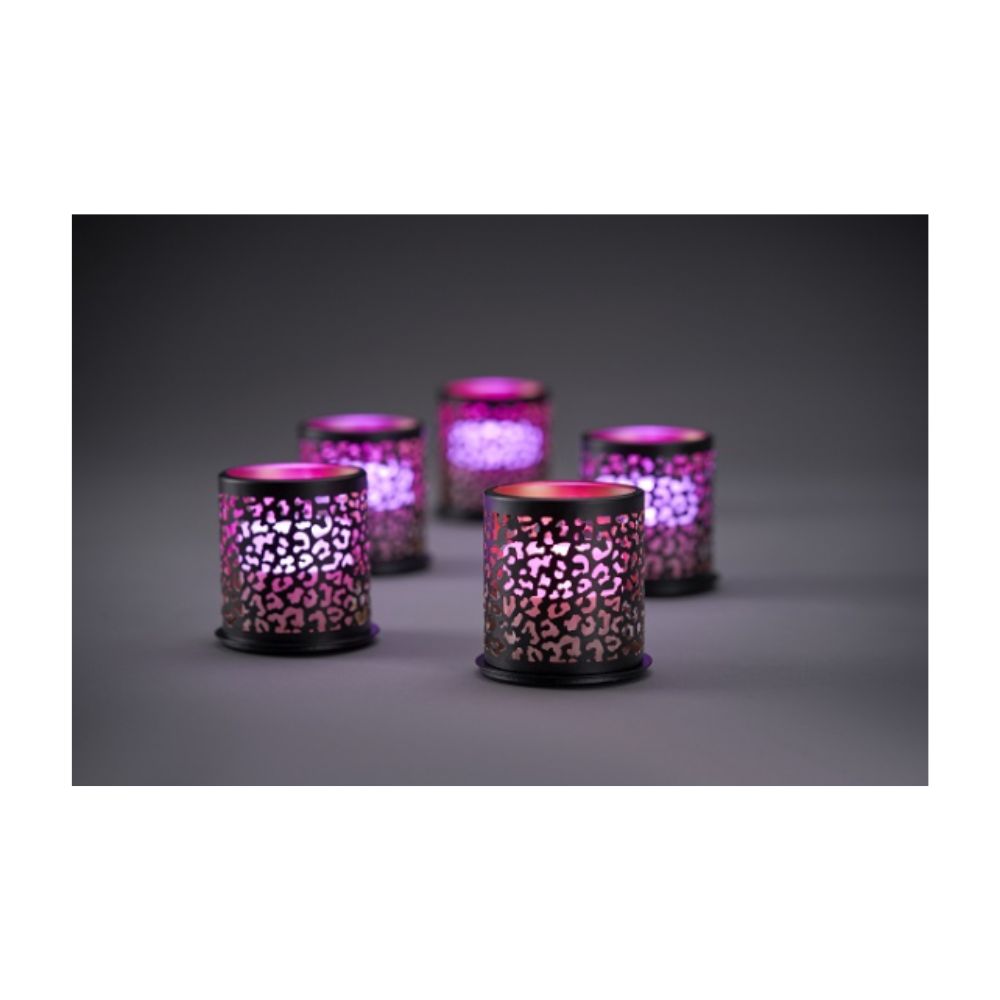 Eight cylindrical mini candle holders from the Duni GmbH Multicolour LED Set illuminate through a cut-out pattern on a gray surface against a dark background.