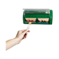 A hand pulls a plaster from a green wall dispenser, the Holthaus Medical Salvequick® plaster dispenser from Holthaus Medical GmbH & Co. KG. The dispenser contains two compartments filled with individually wrapped strips and has a transparent plastic cover at the top.