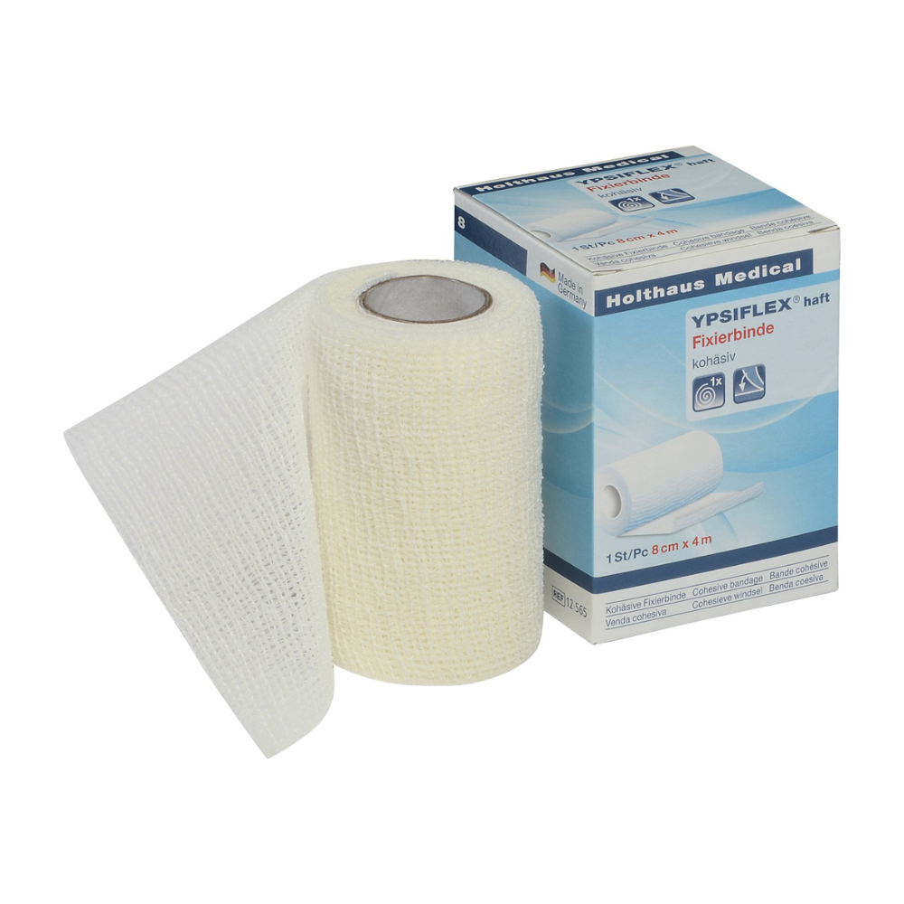 A roll of white elastic medical gauze bandage, partially unrolled, lies next to its packaging box. The box displays the brand "Holthaus Medical GmbH & Co. KG" and the product name "Holthaus YPSIFLEX® adhesive Elastic Gauze Bandage", highlighting its use as a wound dressing fixation. The dimensions of the self-adhesive gauze roll are 8 cm x 4 m.