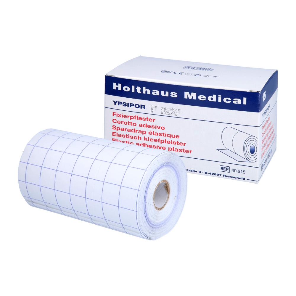 A roll of Holthaus Medical adhesive tape with a grid pattern lies in front of the box labeled "Holthaus Ypsidor". The multilingual description on the packaging highlights the versatile application possibilities.