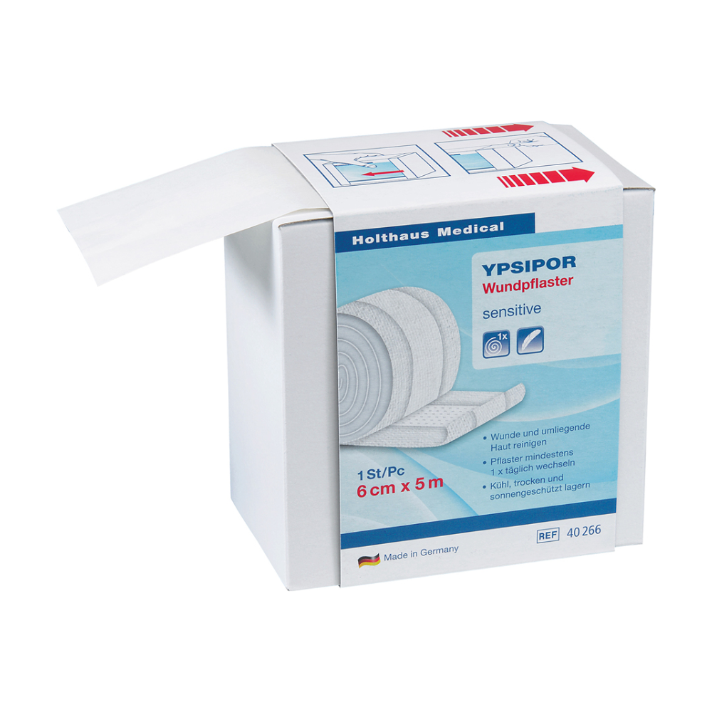 Pictured is a box of Holthaus Ypsipor wound plaster fleece by Holthaus Medical GmbH & Co. KG. The box states that it is sensitive, measures 6 cm x 5 m, and is made in Germany. A part of the skin-friendly fleece wound dressing roll is visible and protrudes from the box.