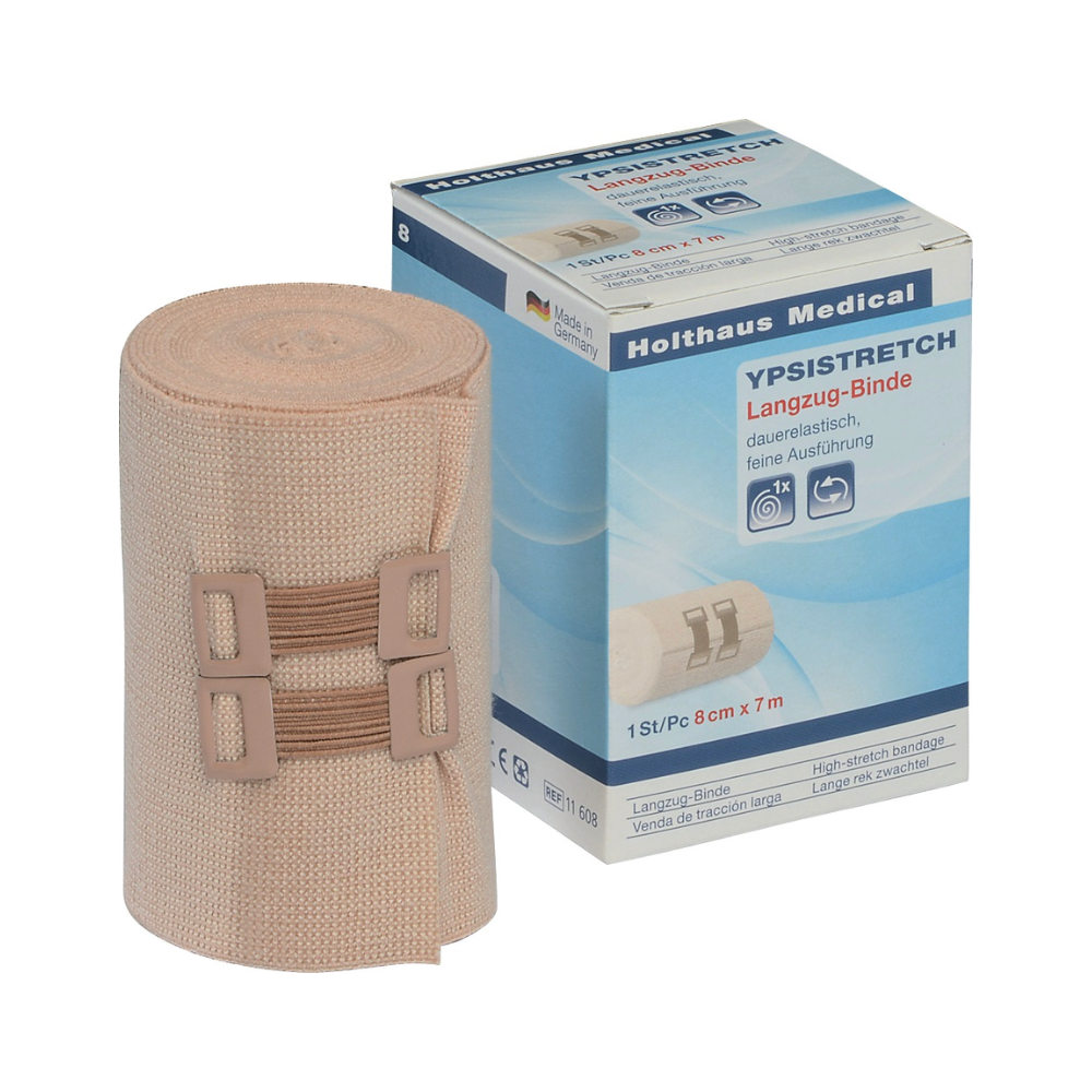 A Holthaus Ypsistretch long-stretch bandage, fine next to its packaging. The beige, permanently elastic bandage is rolled up with two matching fasteners. The packaging displays product information and a picture of the bandage, highlighting its use as a vital medical aid. The dimensions are 8 cm x 7 m from Holthaus Medical GmbH & Co. KG.
