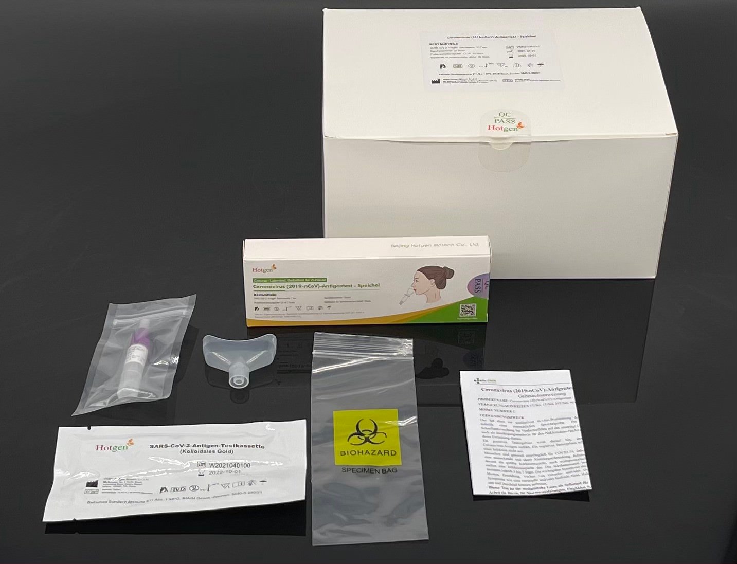 Der HOTGEN Antigentest Speichel (2019-nCoV) | Packung (1 Test) von Hotgen ist übersichtlich auf einer schwarzen Oberfläche angeordnet und enthält einen Tupfer, eine Testkassette, ein Fläschchen mit Extraktionspuffer, einen Probenbeutel, ein Anleitungsblatt und eine Umverpackung. Jeder Artikel in der Packung unterstreicht seine Bedeutung für genaue Tests.