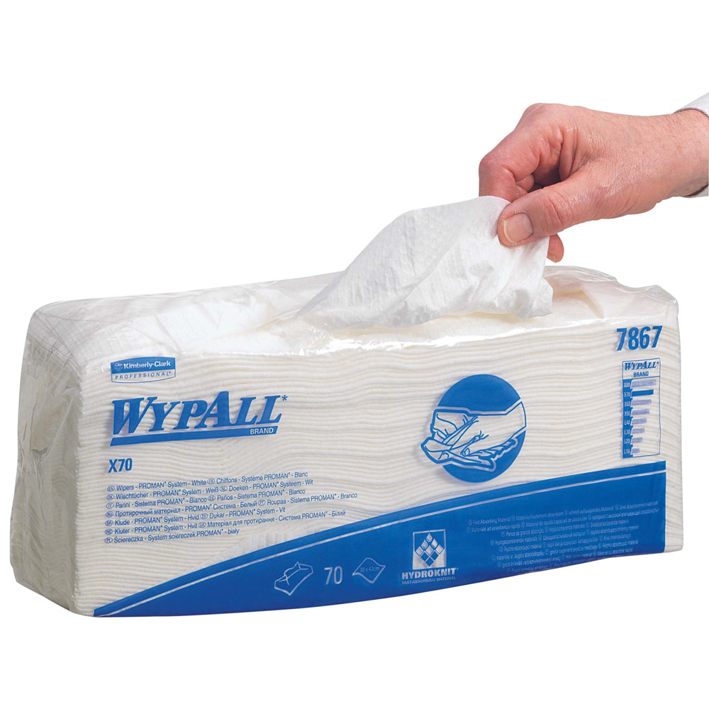 Eine Hand zieht ein WypAll® X70 Wischtuch aus einer rechteckigen Verpackung mit der Aufschrift "WypAll® X70" (70 Tücher, 6 Beutel/Karton) der Kimberly-Clark GmbH. Die meist weiße Verpackung ist mit blauem Text und Grafiken für die industrielle Reinigung versehen.