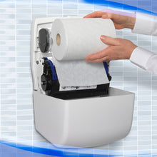 A person loads a large roll of paper towels into the white Aquarius™ Slimroll™ roll towel dispenser from Kimberly-Clark GmbH, which is mounted on a wall with a blue and white tile pattern in the background.