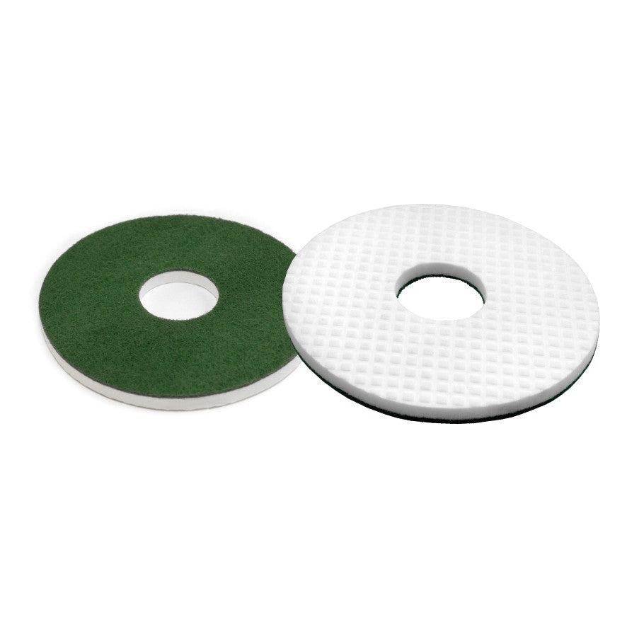 Pictured are two round floor pads: a green pad with a smooth surface and the Arcora MELAMIN ROUND PAD from Arcora International GmbH with a white, structured, mesh-like surface. Both have a central hole for professional cleaning.