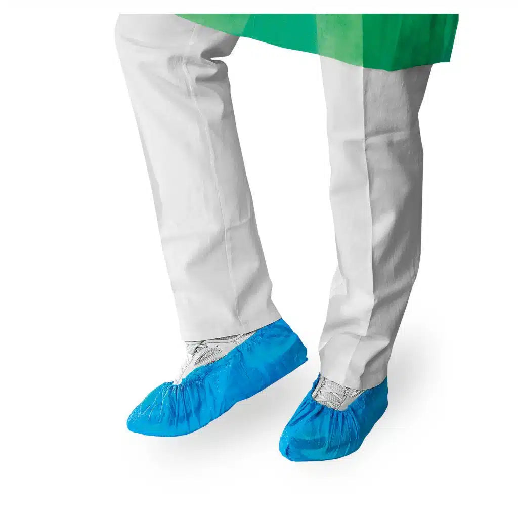 A person in a white lab coat and blue disposable shoe covers from Meditrade GmbH stands in front of a white background, with only their lower legs visible.